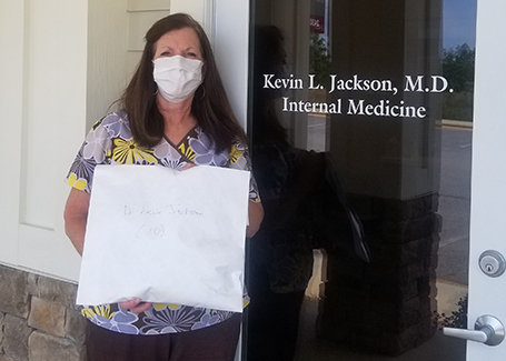 Woman wearing face mask and scrubs holding envelope of donated masks