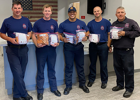 Firemen pose for photo holding bags of donated masks