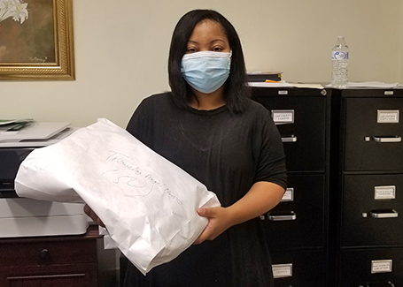 Woman holds up envelope of donated face masks.
