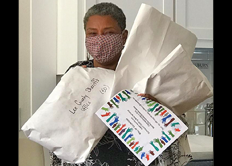Woman wearing face masks holds bags and envelopes of face masks for delivery.