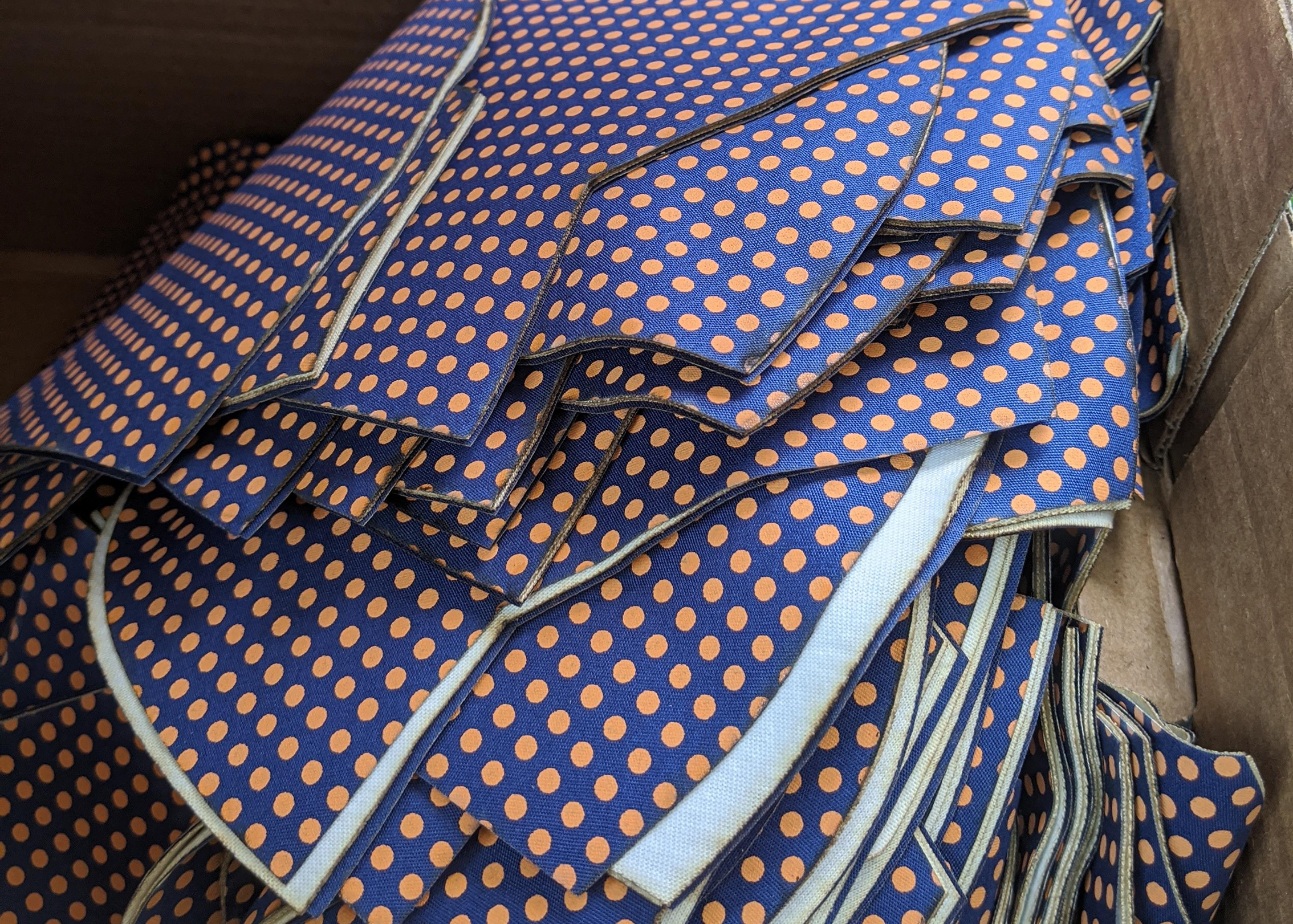 Box of pre-cut mask fabric which is blue with orange dots.