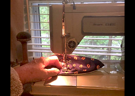 Sewing machine with fabric and needle and person's hand.
