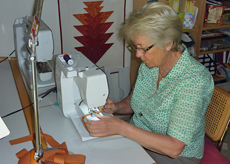 Fenny Dane, OLLI Sewist, sits at her sewing machine working on making face masks.