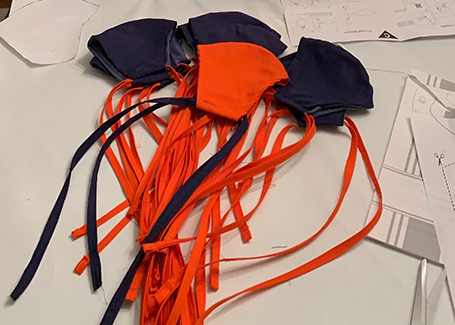 Blue and orange masks with long fabric ties sit on table.