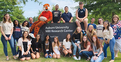 Group photo of campers and Aubie posing by MRI research center sign.