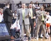 Basketball coach wearing suit shown beside court