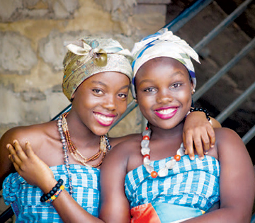 Two african girls pose with arms around each other for photo