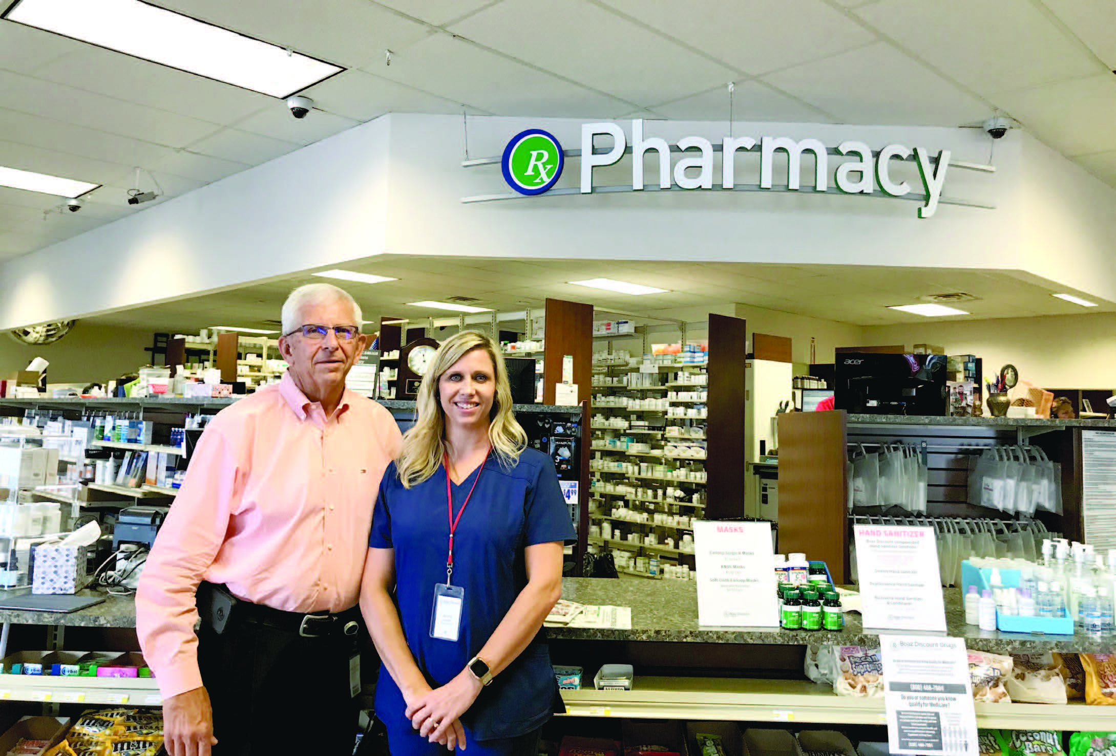 Man and woman pose in front of pharmacy counter