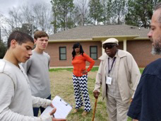 Lee County Youth Development Center's greenhouse planning committee congregates in front of a house.