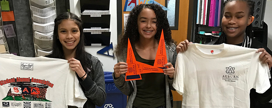 Three female students proudly display Auburn gear during college week at their school