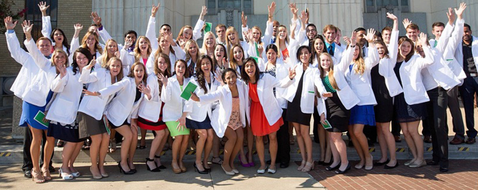 Group photo of students in white lab coats posing for photo