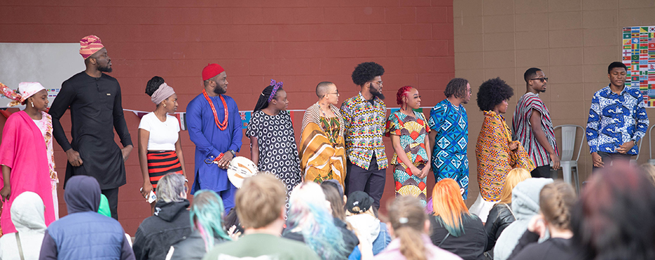 People dressed in African outfits on stage with crowd looking on
