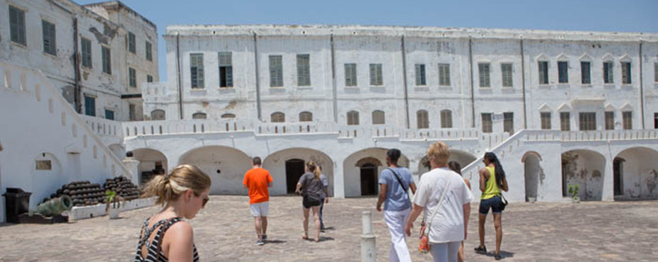 Students walking to a white building (Slave Castle)