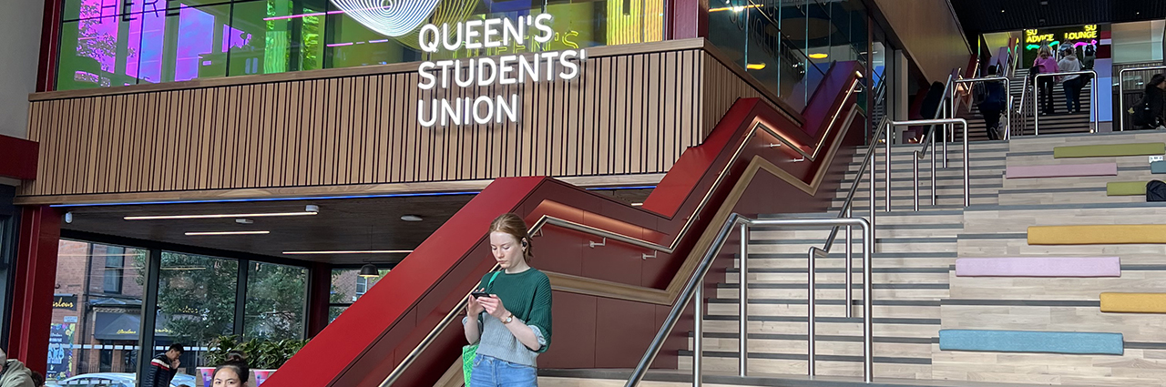 A woman on the stair case inside Queen's Student Union building. 