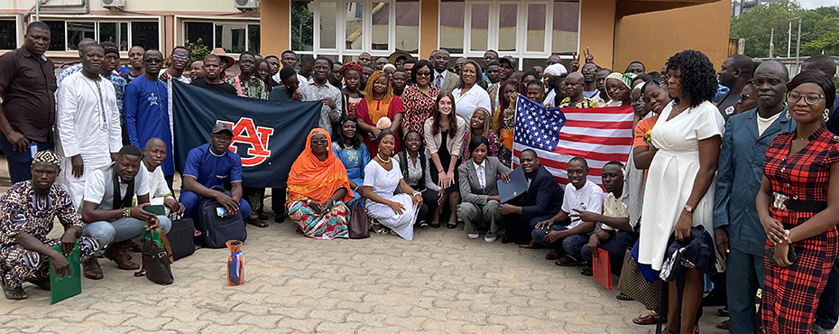 Program participants and Auburn University representatives pose for a photo outside of a building