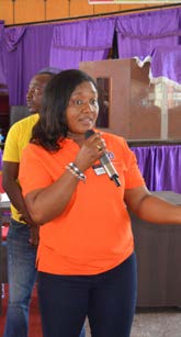 Elizabeth Quansah holds microphone while wearing an orange shirt