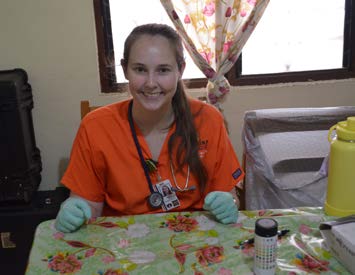 Shelby smiles for the camera wearing scrubs and gloves at the health clinic.
