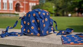 Closeup of orange and blue fabric face mask with blurry Samford Hall in background