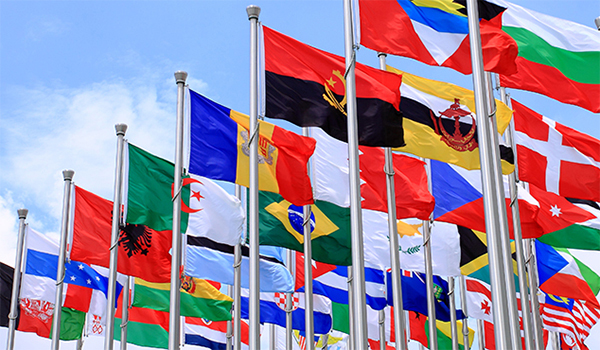 Flag poles with flags from around the world against a blue sky