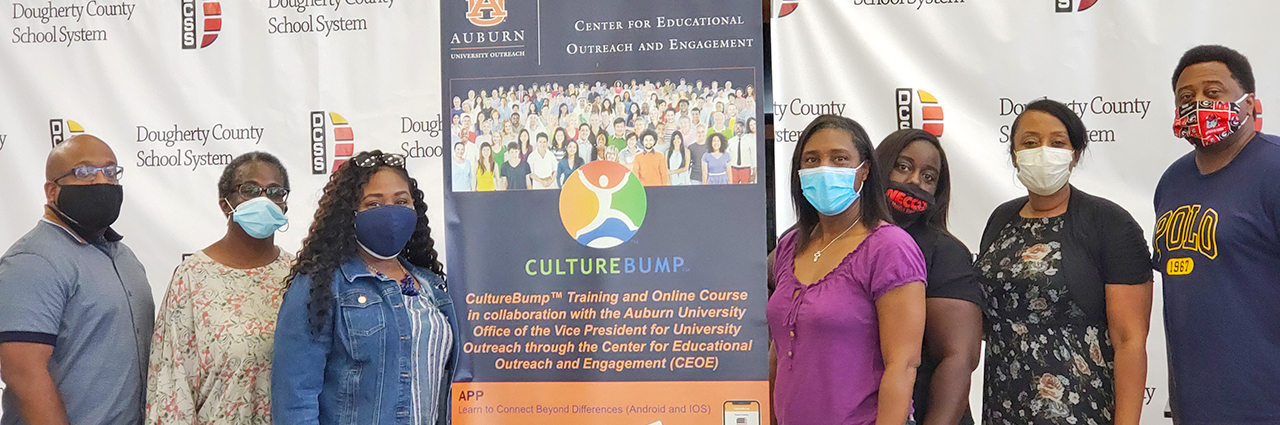 People wearing masks pose for photo with Culture Bump banner during training