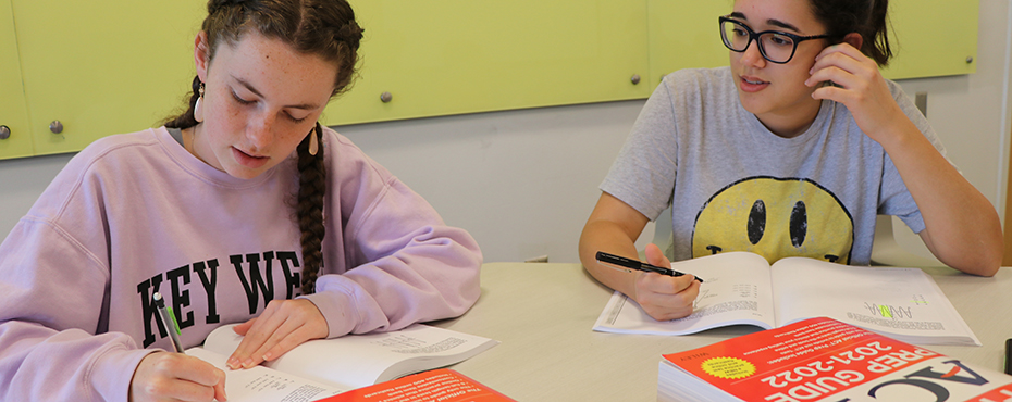 Two female campers do a practice test in their ACT Books.