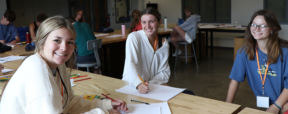 Three female campers pose for a picture in the architect studio.