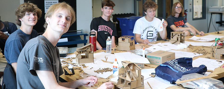 Campers smile for a photo while building multiple cardboard houses in the architect studio.