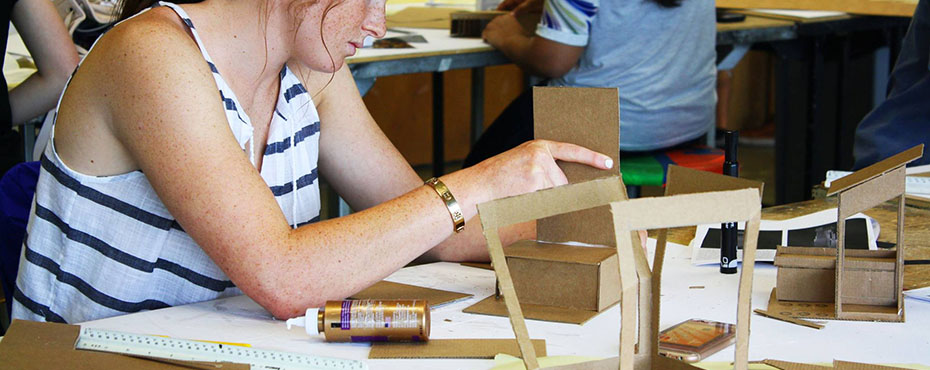 A female student working on constructing a structure with cardboard in the classroom.