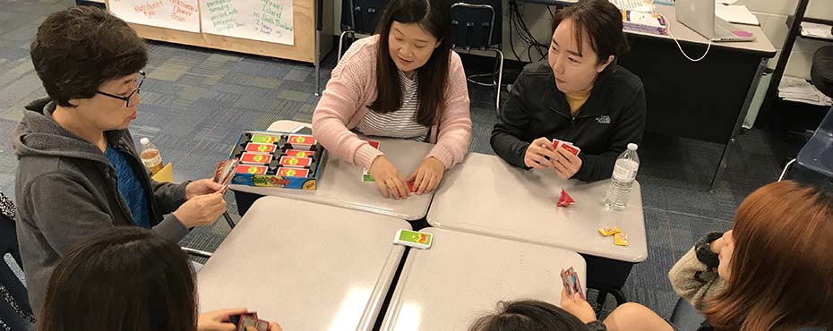 Summer English School students in the Adult Conversation Class play Apples To Apples, a card game, to learn new English words.