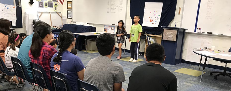 Two Summer English School students present their poster to all of the friends and family that attended their final day presentations.