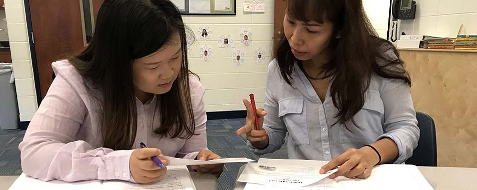 Two Summer English School participants help each other complete a worksheet.