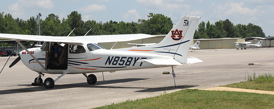 Auburn airplane sits on runway with door open