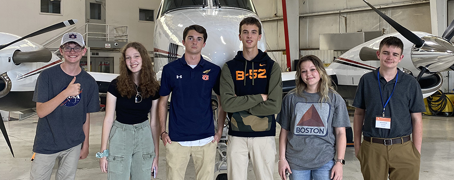 Aviation Campers pose for a photo in an airplane hangar at the Auburn Airport.