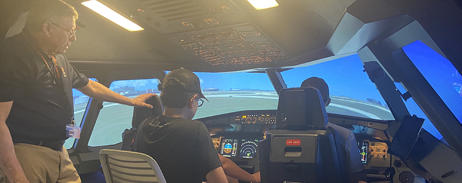 Three students sit in a flight simulator with an Auburn instructor.