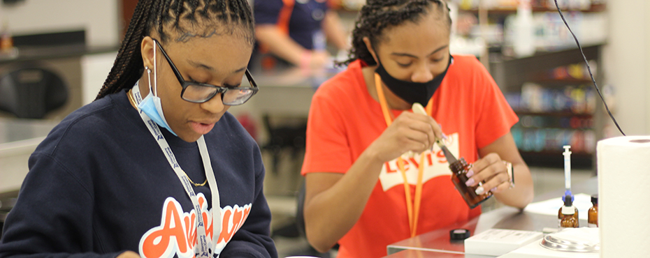 Two girls examine compounds during Discovery Med camp