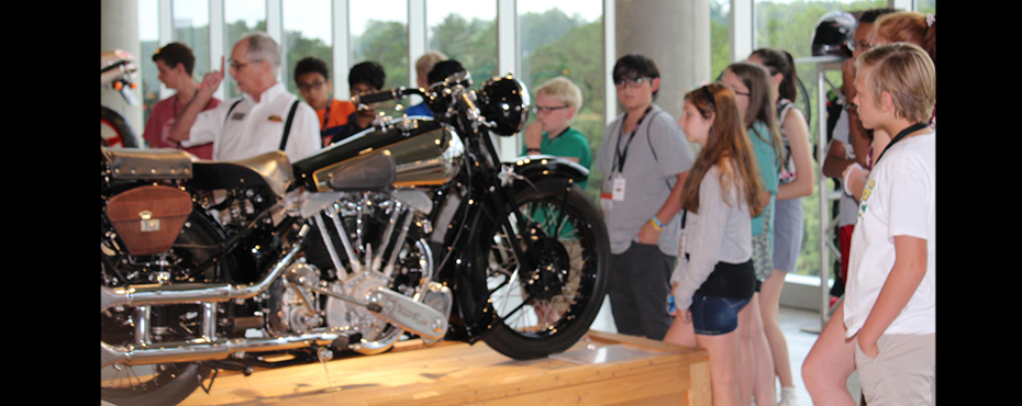 Group tour listening to a guide discuss motorcycle design.