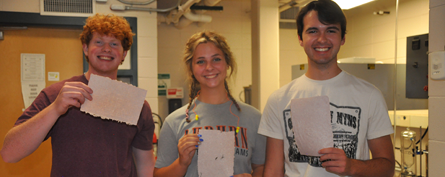 Two male and one female camper holding paper that they made.