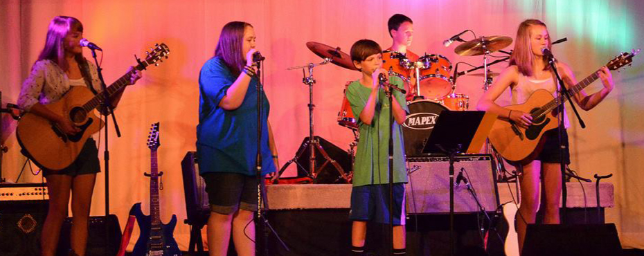 A band of two guitarists, two vocalists, and one drummer rock out on stage during their final performance at Spicer’s Rock Camp.