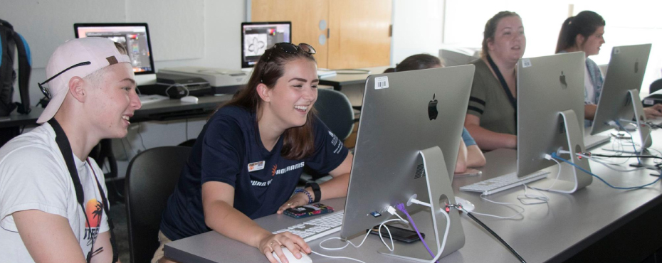 Jessi, an Auburn Youth Programs counselor, helps her campers complete their computer assignment during Creative Photography Camp