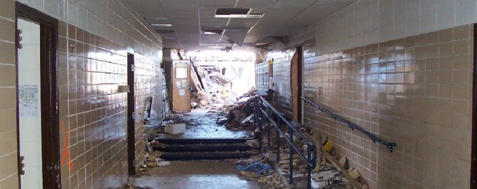 Interior of school hallway looking toward open space where roof collapsed.