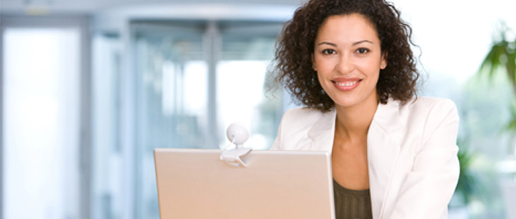 Woman sitting at desk with computer smiling at camera.