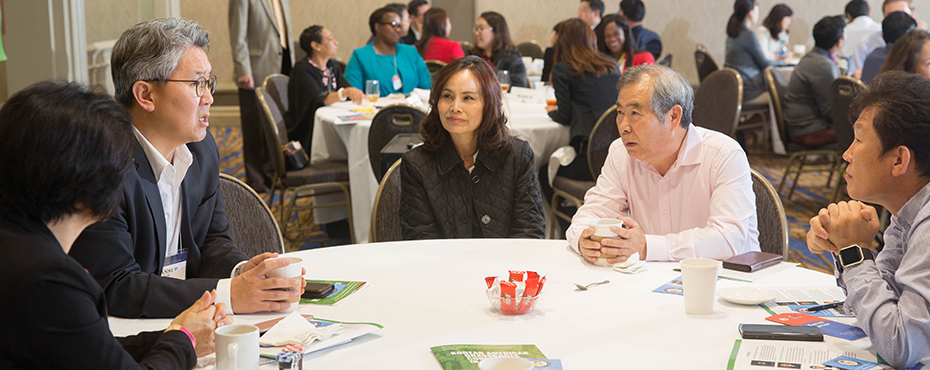 Attendees at the Korean American Grassroots conference sit at tables and network with each other.