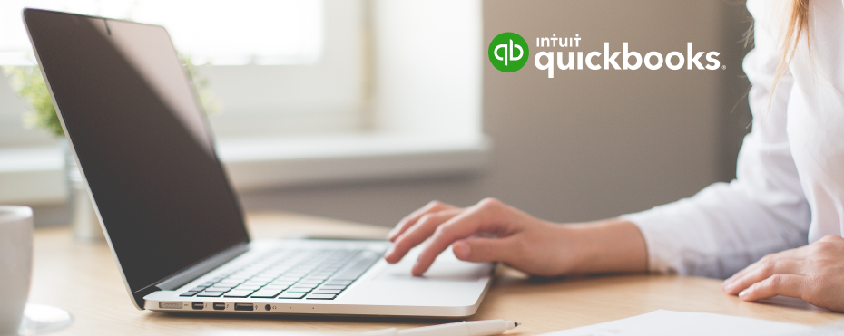 Close-up of woman using laptop with QuickBooks logo.