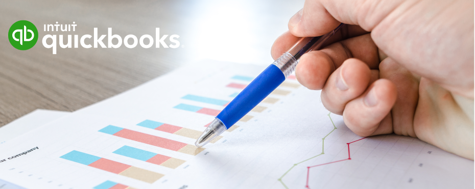 Close-up of person holding pen, reviewing charts with QuickBooks logo.