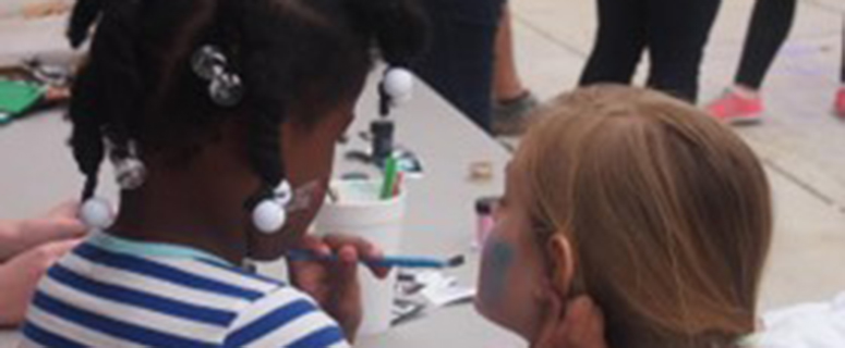 A little girl and volunteer of Project Uplift face painting.