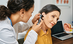 A young woman uses an otoscope to check an older woman's ear canal