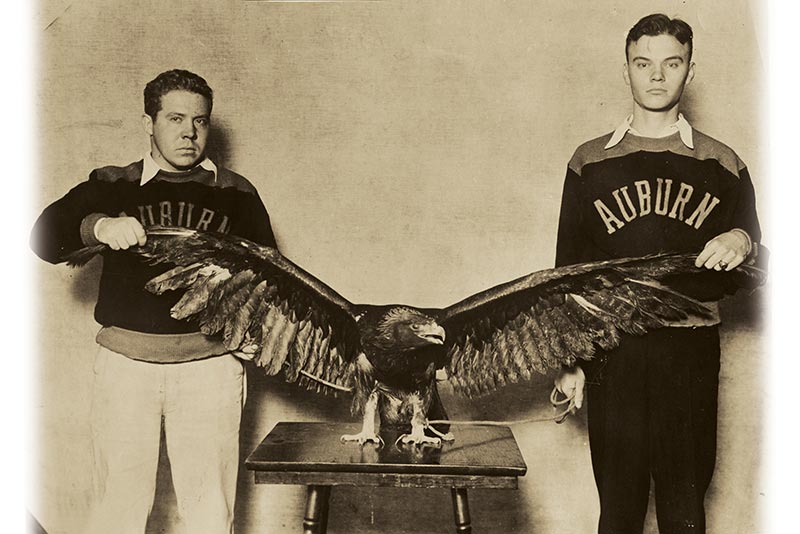 Two students hold an eagle's wings